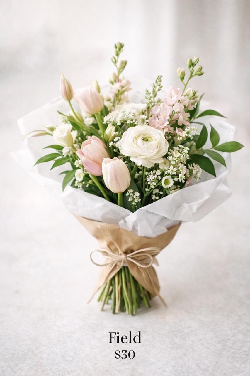 Field tier bouquet with airy seasonal stems and soft romantic tones.